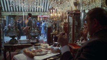 Movie still from “Marathon Man” (1976), directed by John Schlesinger – People are sitting at a table in an antique store; Wide shot, Over the shoulder angle