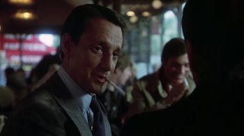 Movie still from “Marathon Man” (1976), directed by John Schlesinger – A person smoking a cigarette in front of other people; Close Up shot, Over the shoulder angle