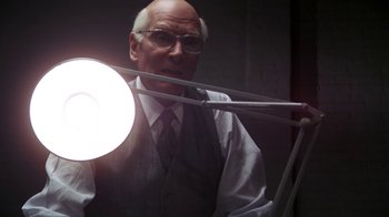 Movie still from “Marathon Man” (1976), directed by John Schlesinger – An older man in a vest and tie holding a light; Medium shot, Low angle