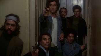 Movie still from “Marathon Man” (1976), directed by John Schlesinger – A group of men holding guns in front of a wall; Medium shot, Low angle