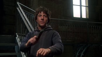 Movie still from “Marathon Man” (1976), directed by John Schlesinger – A young man holding a tie while standing next to a staircase; Medium shot, Low angle