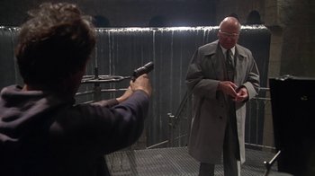 Movie still from “Marathon Man” (1976), directed by John Schlesinger – A man holding a gun while standing next to another man; Medium shot, Over the shoulder angle