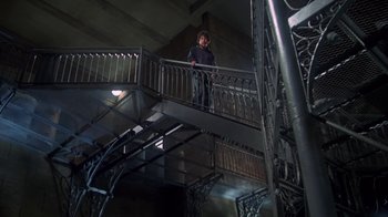 Movie still from “Marathon Man” (1976), directed by John Schlesinger – A man standing on top of a metal railing next to stairs; Wide shot, Low angle