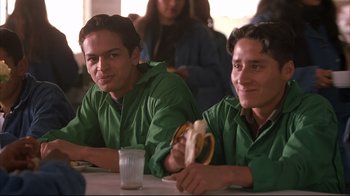 Movie still from “Maria Full of Grace” (2004), directed by Joshua Marston – Two young men sitting at a table with a sandwich; Medium shot, Low angle