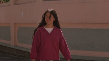 Movie still from “Maria Full of Grace” (2004), directed by Joshua Marston – A young woman in a pink sweatshirt is walking; Medium shot, Low angle