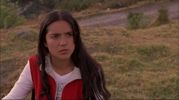 Movie still from “Maria Full of Grace” (2004), directed by Joshua Marston – A young woman in a red jacket is standing in the grass; Close Up shot, Over the shoulder angle