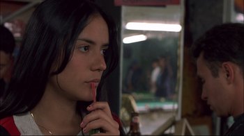 Movie still from “Maria Full of Grace” (2004), directed by Joshua Marston – A woman holding a drink in her hand and looking at the camera; Close Up shot, Over the shoulder angle