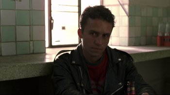 Movie still from “Maria Full of Grace” (2004), directed by Joshua Marston – A man sitting in front of a window holding a drink; Close Up shot, Low angle