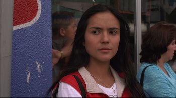 Movie still from “Maria Full of Grace” (2004), directed by Joshua Marston – A woman with long black hair standing in front of a building; Close Up shot, Low angle