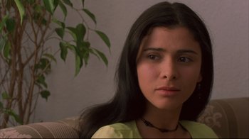 Movie still from “Maria Full of Grace” (2004), directed by Joshua Marston – A person sitting on a couch near a plant; Close Up shot, Low angle