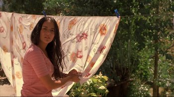 Movie still from “Maria Full of Grace” (2004), directed by Joshua Marston – A woman hanging up a sheet on a clothes line; Medium shot, Low angle