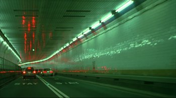 Movie still from “Maria Full of Grace” (2004), directed by Joshua Marston – Cars driving down a highway in a tunnel; Extreme Wide shot, High angle