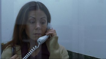 Movie still from “Maria Full of Grace” (2004), directed by Joshua Marston – A woman is talking on a phone behind a glass; Close Up shot, High angle