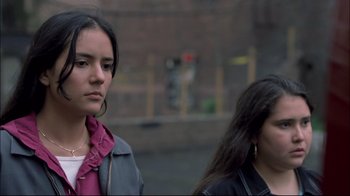 Movie still from “Maria Full of Grace” (2004), directed by Joshua Marston – Two young women standing next to each other on the sidewalk; Close Up shot, Over the shoulder angle