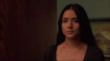 Movie still from “Maria Full of Grace” (2004), directed by Joshua Marston – A woman with a cross necklace is posing for a picture; Close Up shot, Over the shoulder angle