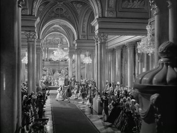 Movie still from “Marie Antoinette” (1938), directed by Julien Duvivier – A black - and - white photo of a crowd of people in an ornate hall; Extreme Wide shot, High angle