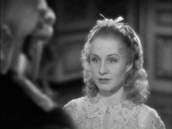Movie still from “Marie Antoinette” (1938), directed by Julien Duvivier – A black and white photo of a woman with a bow in her hair; Close Up shot, Over the shoulder angle