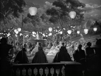 Movie still from “Marie Antoinette” (1938), directed by Julien Duvivier – A black and white photo of people sitting in front of a fountain; Extreme Wide shot, High angle