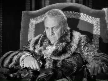 Movie still from “Marie Antoinette” (1938), directed by Julien Duvivier – An older man sitting in a chair wearing a fur coat; Medium shot, Low angle