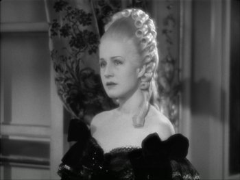 Movie still from “Marie Antoinette” (1938), directed by Julien Duvivier – A young woman with long blonde ringlets in a black dress; Close Up shot, High angle