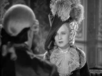 Movie still from “Marie Antoinette” (1938), directed by Julien Duvivier – An old photo of a woman wearing a hat with a pom - poms; Close Up shot, Over the shoulder angle