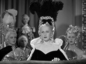 Movie still from “Marie Antoinette” (1938), directed by Julien Duvivier – A group of people in costumes sitting around a table; Medium shot, Over the shoulder angle