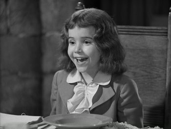 Movie still from “Marie Antoinette” (1938), directed by Julien Duvivier – A little girl sitting at a table with a plate of food in front of her; Medium shot, High angle