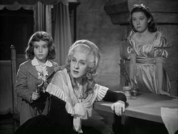 Movie still from “Marie Antoinette” (1938), directed by Julien Duvivier – A woman and two young girls are sitting on a table; Medium shot, High angle