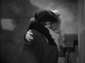 Movie still from “Marie Antoinette” (1938), directed by Julien Duvivier – Two women embracing each other in front of a dark background; Medium shot, High angle