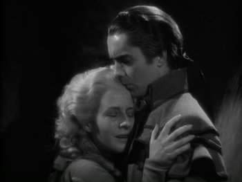 Movie still from “Marie Antoinette” (1938), directed by Julien Duvivier – A man and a woman embracing each other in a black and white photo; Medium shot, Low angle