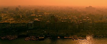Movie still from “Extraction” (2020), directed by Sam Hargrave – An aerial view of a large city at sunset; Extreme Wide shot, High angle