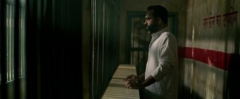 Movie still from “Extraction” (2020), directed by Sam Hargrave – A man standing in front of a window; Medium shot, Low angle