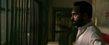 Movie still from “Extraction” (2020), directed by Sam Hargrave – A man standing next to a cage in a room; Close Up shot, Over the shoulder angle