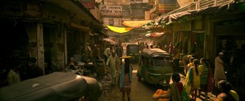 Movie still from “Extraction” (2020), directed by Sam Hargrave – A street scene with people walking and cars on it; Extreme Wide shot, High angle