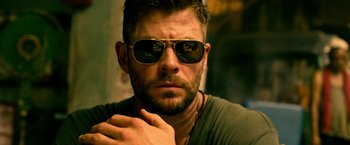 Movie still from “Extraction” (2020), directed by Sam Hargrave – A person wearing sunglasses; Close Up shot, Low angle