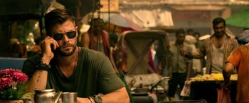 Movie still from “Extraction” (2020), directed by Sam Hargrave – A man sitting at a table in front of a mirror; Medium shot, Over the shoulder angle