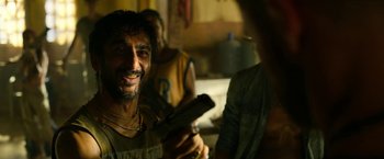 Movie still from “Extraction” (2020), directed by Sam Hargrave – A man smiles while holding a cell phone; Close Up shot, Over the shoulder angle