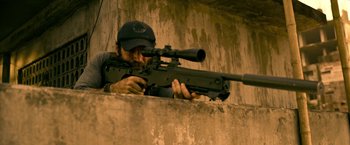 Movie still from “Extraction” (2020), directed by Sam Hargrave – A man with a rifle aiming at a building; Medium shot, High angle