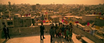 Movie still from “Extraction” (2020), directed by Sam Hargrave – A group of people standing on top of a building; Wide shot, Overhead angle