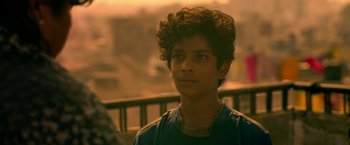 Movie still from “Extraction” (2020), directed by Sam Hargrave – A young man is looking into the distance; Close Up shot, Over the shoulder angle