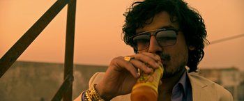 Movie still from “Extraction” (2020), directed by Sam Hargrave – A man with glasses is drinking a drink; Close Up shot, Low angle