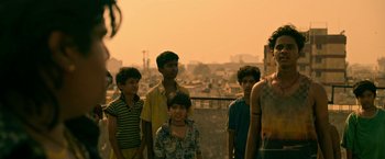 Movie still from “Extraction” (2020), directed by Sam Hargrave – A group of young people standing on top of a building; Medium shot, Over the shoulder angle