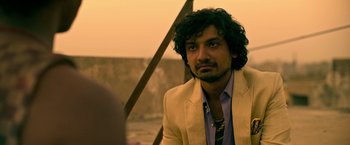 Movie still from “Extraction” (2020), directed by Sam Hargrave – A person wearing a suit and tie; Close Up shot, Over the shoulder angle