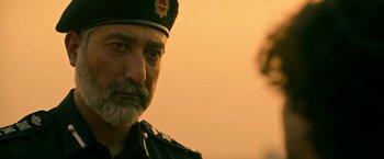 Movie still from “Extraction” (2020), directed by Sam Hargrave – A person wearing a uniform; Close Up shot, Low angle