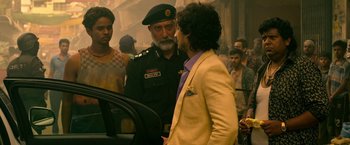 Movie still from “Extraction” (2020), directed by Sam Hargrave – A man in a yellow jacket talking to a man in a purple shirt; Medium shot, Over the shoulder angle