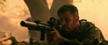 Movie still from “Extraction” (2020), directed by Sam Hargrave – A person holding a gun; Close Up shot, Low angle