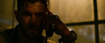 Movie still from “Extraction” (2020), directed by Sam Hargrave – A person talking on a cell phone; Close Up shot, Low angle