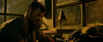 Movie still from “Extraction” (2020), directed by Sam Hargrave – A person sitting at a desk; Close Up shot, Over the shoulder angle