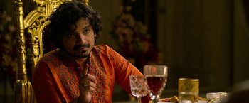 Movie still from “Extraction” (2020), directed by Sam Hargrave – A man sitting in front of a glass of wine; Close Up shot, Over the shoulder angle