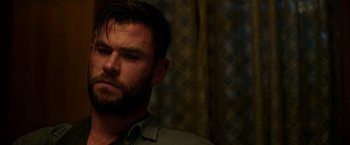 Movie still from “Extraction” (2020), directed by Sam Hargrave – A person with a beard; Close Up shot, Over the shoulder angle